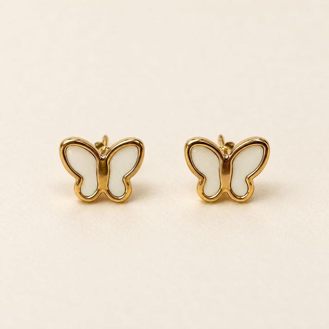Ivory enamel butterfly stud earrings with gold-tone edging on cream